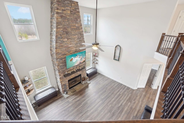 living area with a towering ceiling, a fireplace, baseboards, and wood finished floors