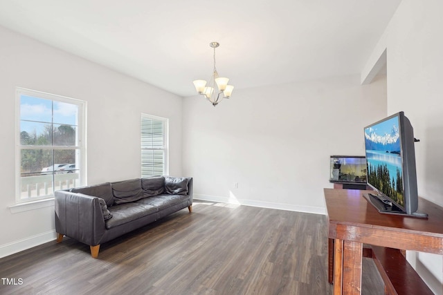 living room with baseboards, a notable chandelier, and wood finished floors