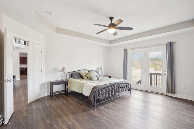 bedroom with access to exterior, a raised ceiling, a ceiling fan, wood finished floors, and baseboards