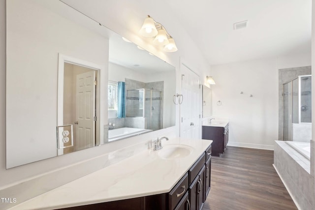 full bathroom featuring a shower stall, vanity, wood finished floors, baseboards, and a bath