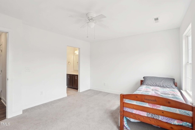 bedroom with light carpet, visible vents, baseboards, ensuite bath, and ceiling fan