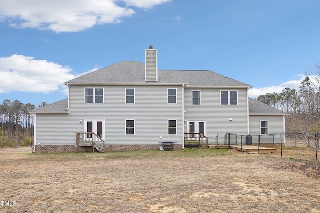 back of house with a yard, a wooden deck, a chimney, and french doors