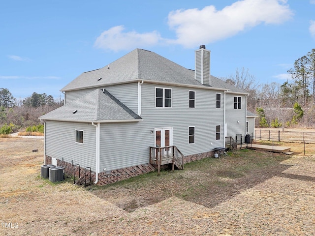 rear view of property featuring french doors, roof with shingles, fence, and a chimney