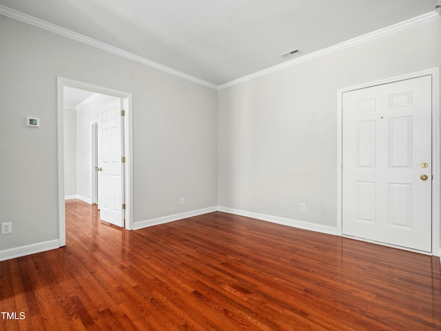 unfurnished room featuring dark wood-style floors, visible vents, ornamental molding, and baseboards