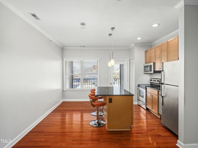 kitchen with visible vents, dark countertops, a center island, stainless steel appliances, and a kitchen bar