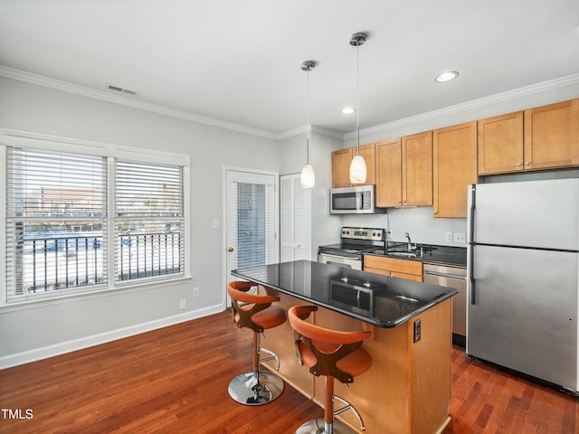 kitchen featuring stainless steel appliances, a center island, dark countertops, a kitchen bar, and pendant lighting