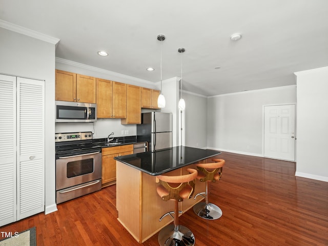 kitchen with a breakfast bar, a kitchen island, appliances with stainless steel finishes, dark countertops, and pendant lighting