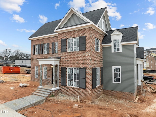 view of front of house featuring a shingled roof and brick siding