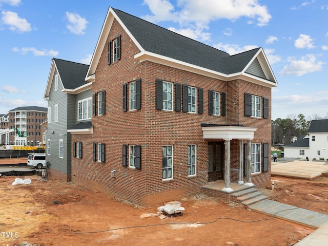 view of front of house featuring brick siding and roof with shingles