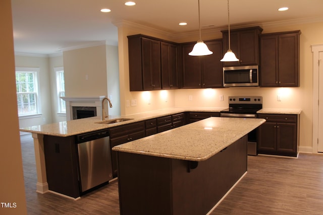 kitchen featuring pendant lighting, sink, a center island, kitchen peninsula, and stainless steel appliances