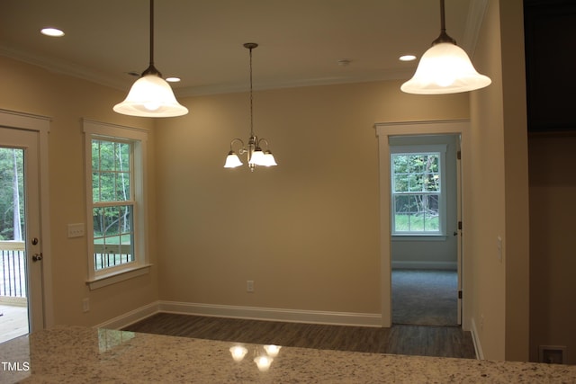 unfurnished dining area with an inviting chandelier, ornamental molding, and dark hardwood / wood-style floors