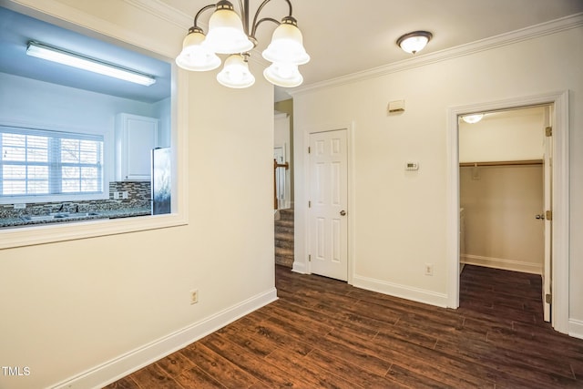 interior space with baseboards, stainless steel fridge, ornamental molding, a chandelier, and dark wood finished floors
