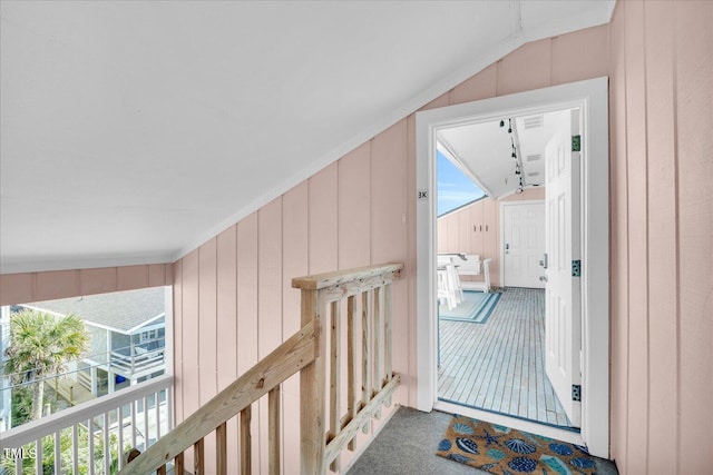 interior space with carpet, lofted ceiling, and wood walls