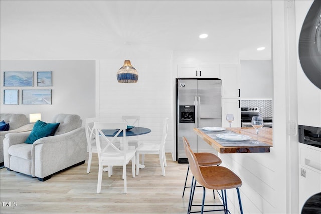 dining room with stacked washer / dryer and light hardwood / wood-style floors