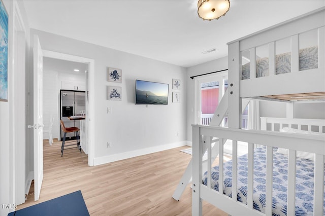 bedroom with hardwood / wood-style flooring and stainless steel fridge