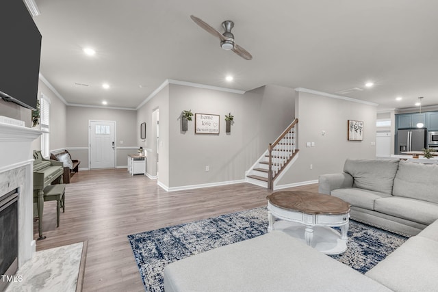 living area featuring light wood-style flooring, recessed lighting, a fireplace, and stairway