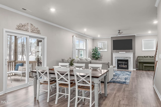 dining room featuring a ceiling fan, crown molding, visible vents, and wood finished floors