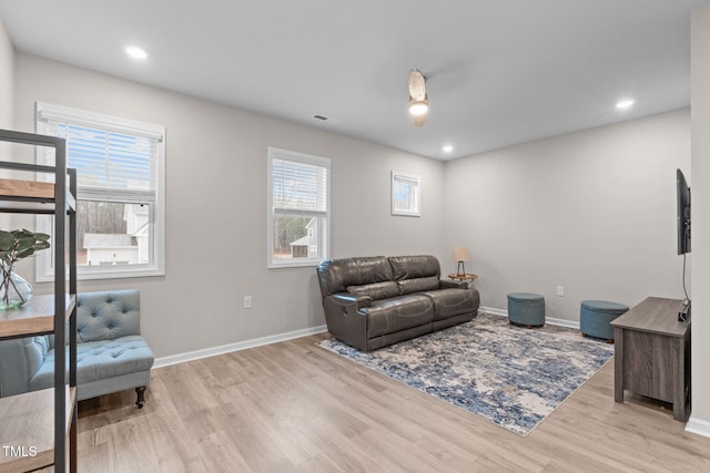 living area featuring a healthy amount of sunlight, visible vents, light wood-style flooring, and baseboards