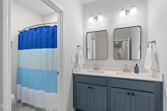 bathroom featuring a shower with curtain, a sink, toilet, and double vanity