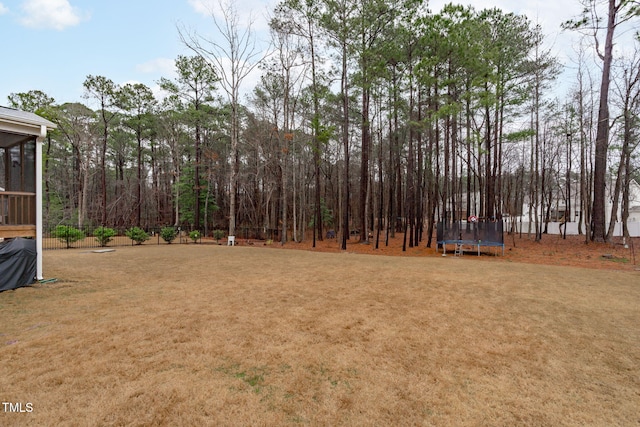 view of yard featuring a trampoline and a sunroom