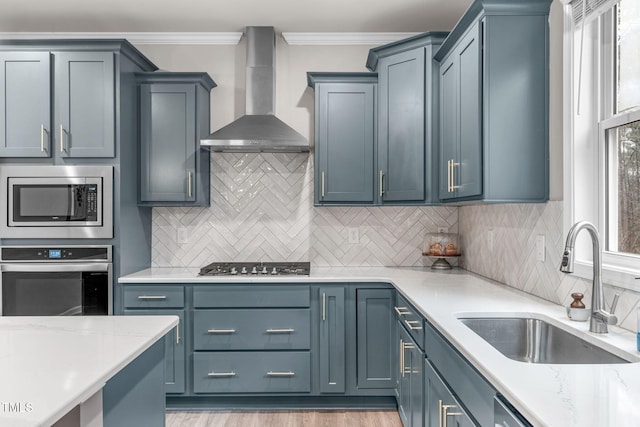 kitchen featuring decorative backsplash, wall chimney exhaust hood, ornamental molding, stainless steel appliances, and a sink