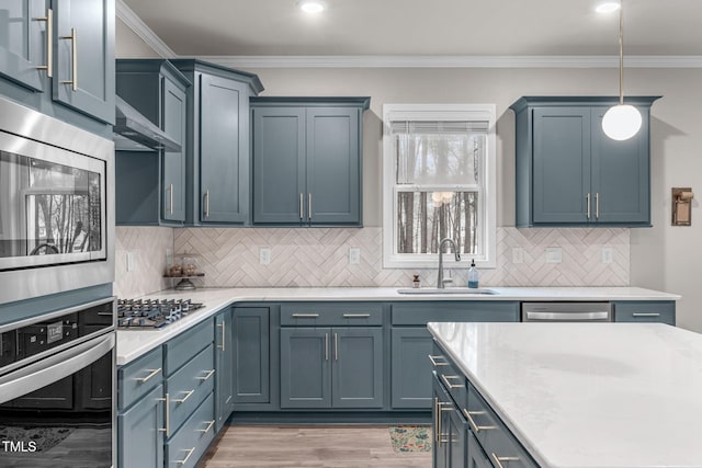 kitchen with pendant lighting, crown molding, stainless steel appliances, light countertops, and a sink