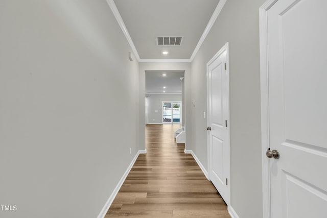 hallway with ornamental molding and light hardwood / wood-style floors