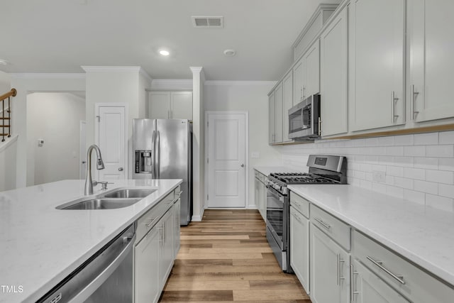 kitchen with light hardwood / wood-style flooring, stainless steel appliances, backsplash, ornamental molding, and sink