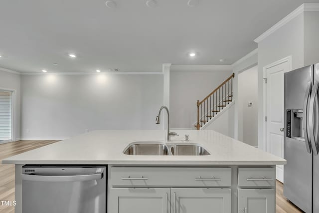 kitchen featuring appliances with stainless steel finishes, light hardwood / wood-style flooring, ornamental molding, sink, and a kitchen island with sink