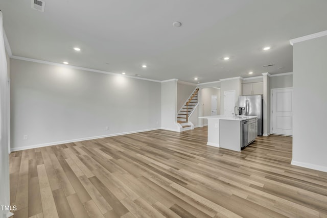 unfurnished living room featuring light wood-type flooring, crown molding, and sink