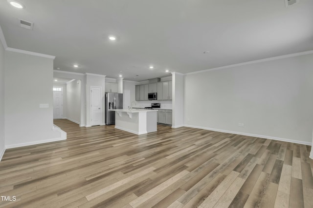 unfurnished living room with ornamental molding, sink, and light wood-type flooring