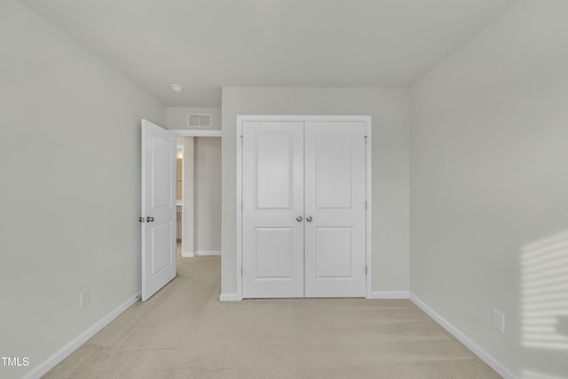 unfurnished bedroom featuring a closet and light colored carpet