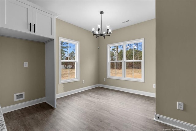 unfurnished dining area featuring dark hardwood / wood-style flooring and a chandelier