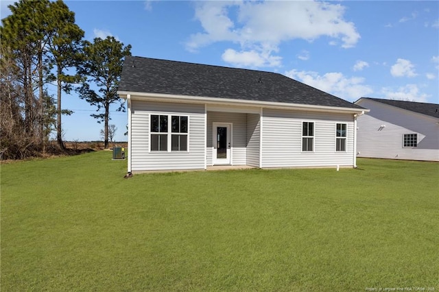 rear view of house featuring central AC, a shingled roof, and a lawn