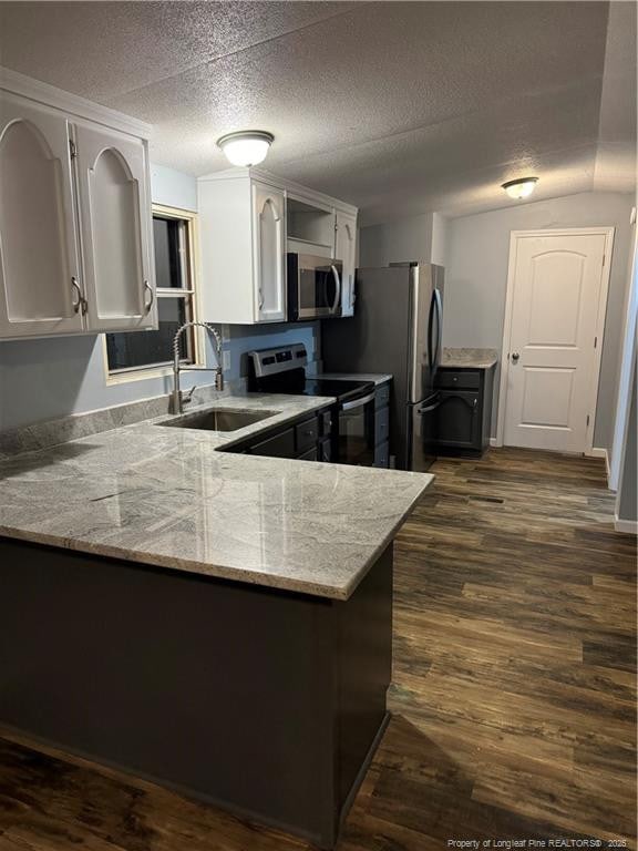 kitchen featuring appliances with stainless steel finishes, dark hardwood / wood-style floors, sink, white cabinets, and kitchen peninsula