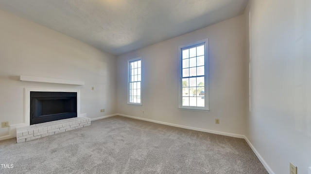 unfurnished living room with vaulted ceiling, a brick fireplace, and light colored carpet