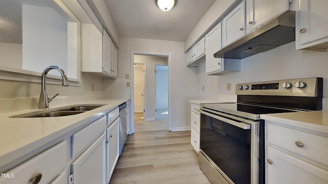 kitchen featuring appliances with stainless steel finishes, light wood-type flooring, a textured ceiling, sink, and white cabinetry