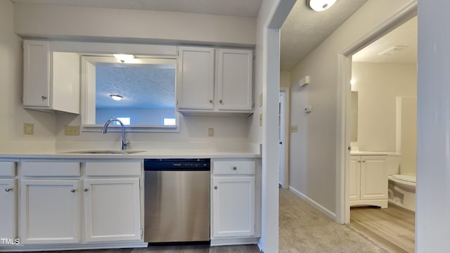 kitchen featuring stainless steel dishwasher, sink, and white cabinets