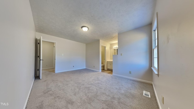 empty room with a textured ceiling and light colored carpet