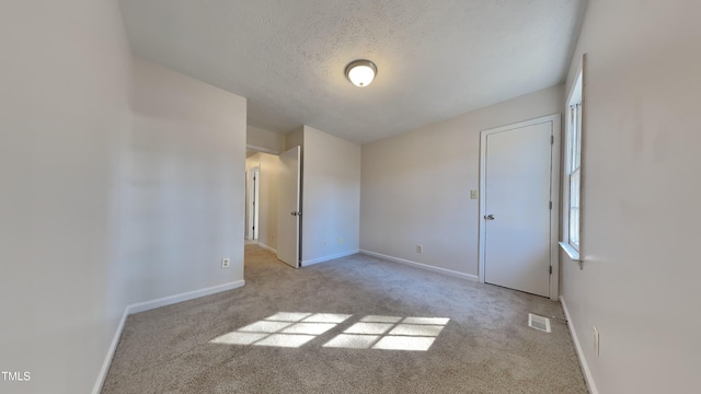 empty room featuring light carpet and a textured ceiling