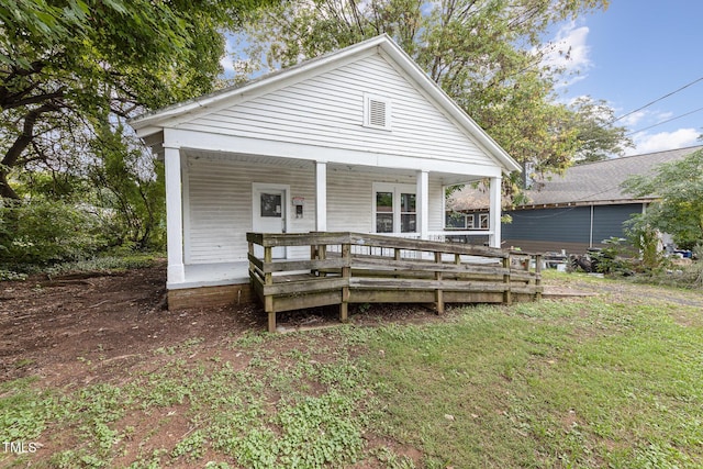 back of property featuring covered porch and a lawn