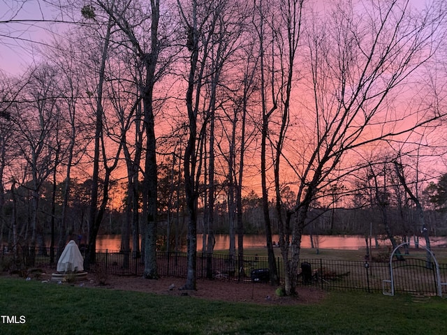 yard at dusk with a water view and fence