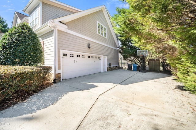 view of home's exterior with an attached garage, stone siding, and concrete driveway