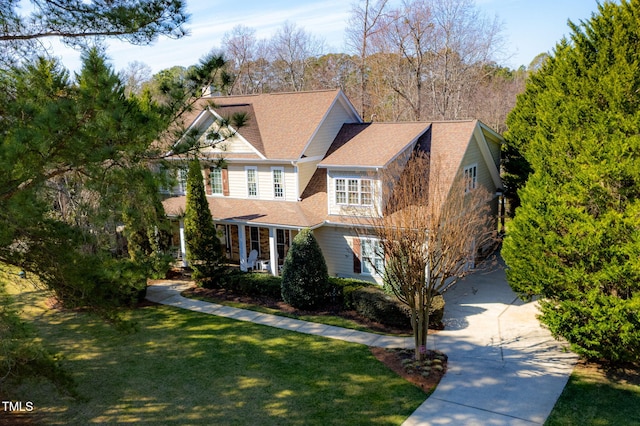 view of front of property with a front yard, concrete driveway, and covered porch