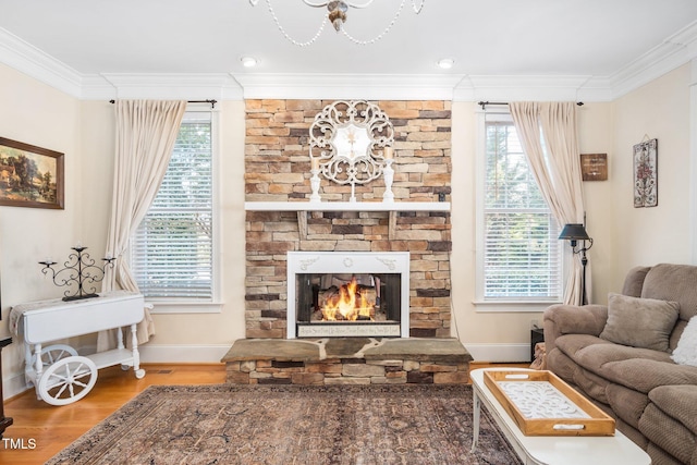 living area featuring ornamental molding, a fireplace, wood finished floors, and baseboards