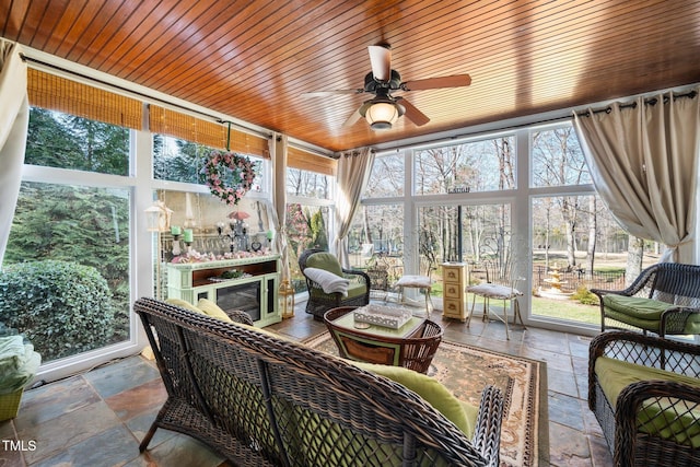 sunroom / solarium with a healthy amount of sunlight, wooden ceiling, and ceiling fan