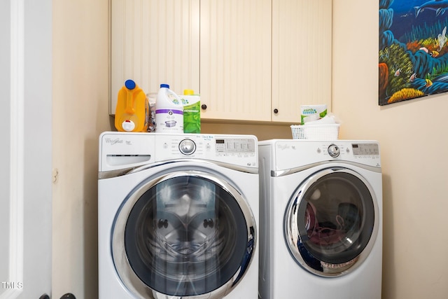 clothes washing area featuring washing machine and dryer and cabinet space