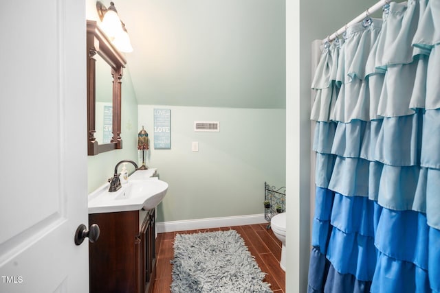 bathroom featuring lofted ceiling, vanity, visible vents, baseboards, and wood tiled floor