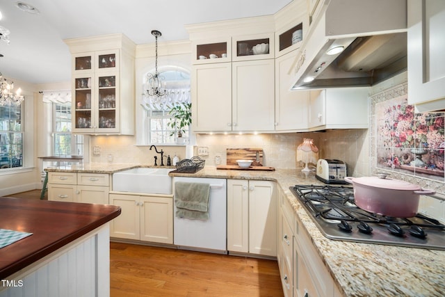 kitchen featuring stainless steel gas cooktop, a notable chandelier, a sink, dishwasher, and extractor fan