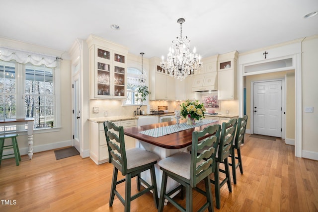 dining area featuring light wood-type flooring, baseboards, and a chandelier